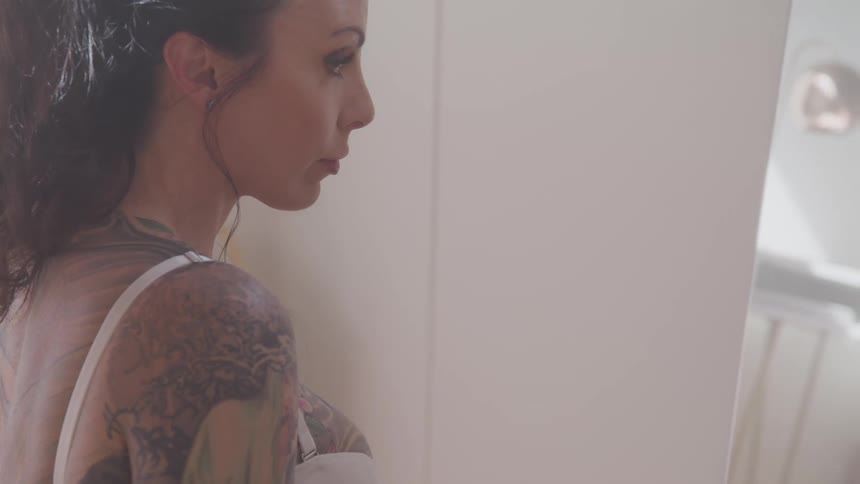 Tattooed woman sitting on the rug looks in the mirror