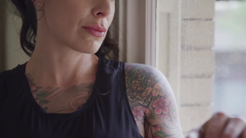 A woman with tattoos is sitting by the window