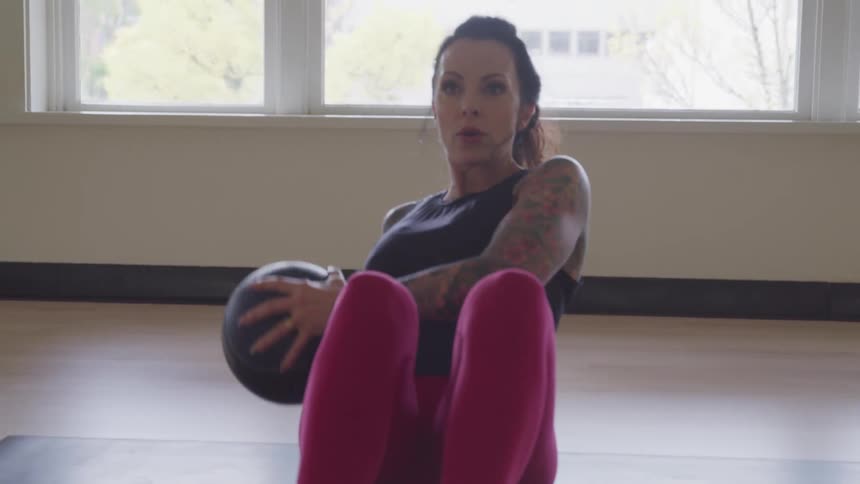 A woman exercise with a weighted ball