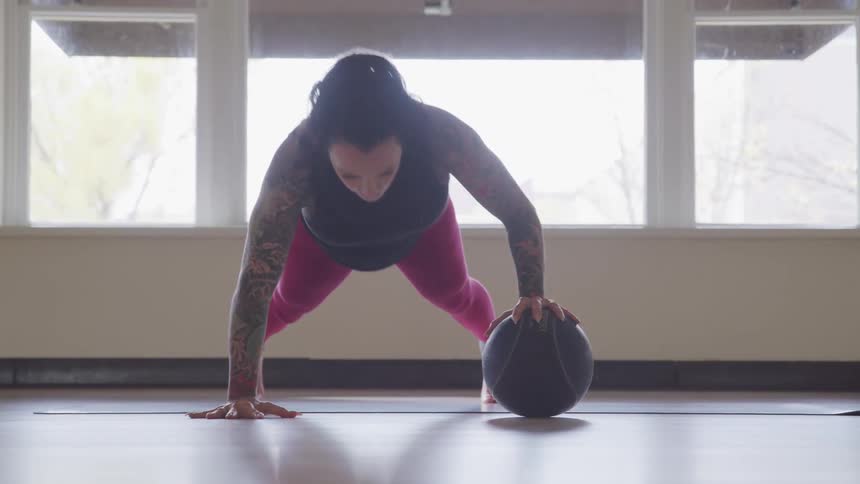 A woman doing push ups using an exercise ball