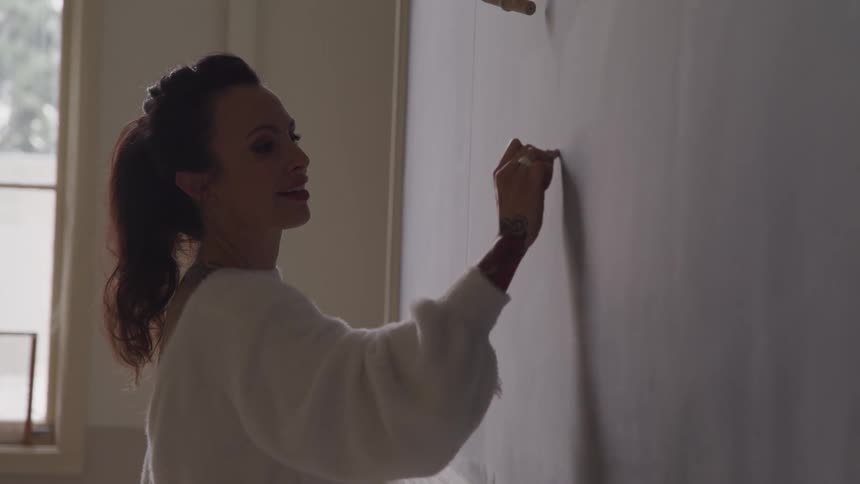 Woman writes on chalkboard in the class