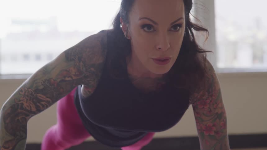 Heavily tattooed woman does a plank at home