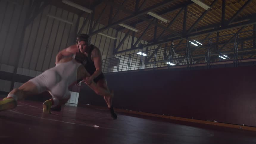 Two teenagers compete in a wrestling match in a school gymnasium