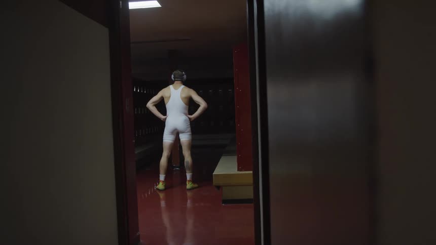 A teenager wrestler stands in a locker room