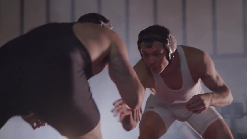 Two wrestlers shake hands before starting bout in foggy room