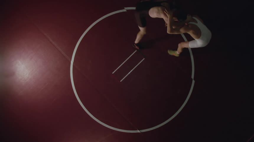 Two men in a leotard shaking hands then wrestling