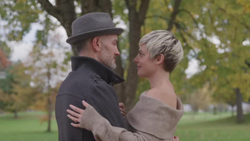 Man and woman embrace as they stand in a park