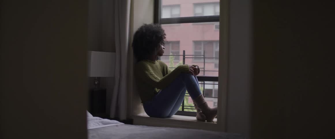 A woman sits on the windowsill in the bedroom