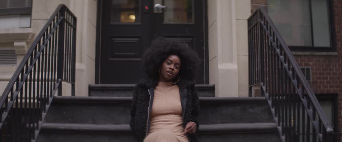A woman is sitting on the steps of her home
