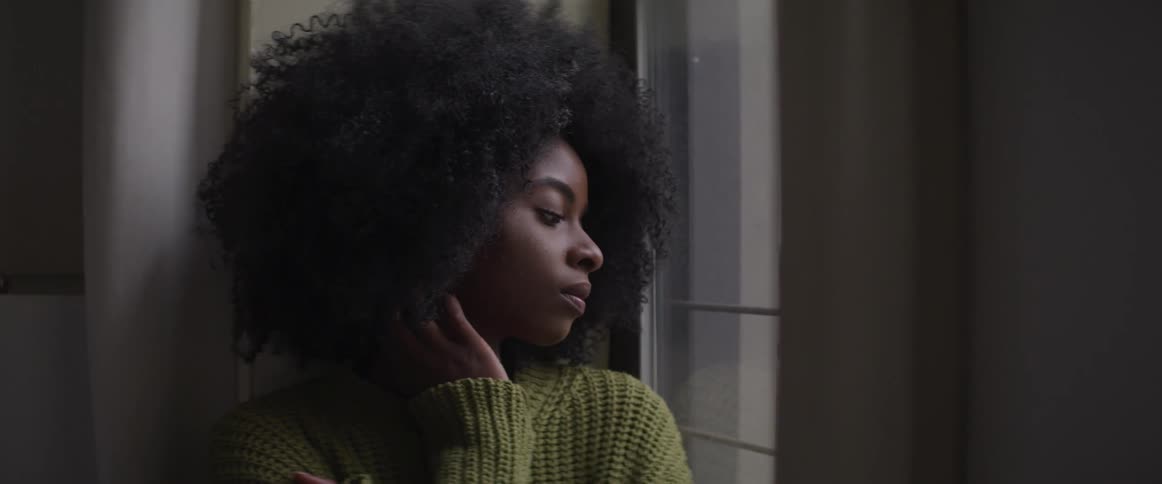 A black woman looks out a window