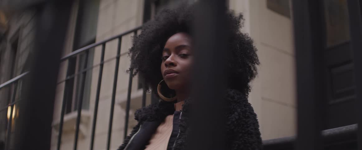 Young black woman sitting on front steps of apartment building