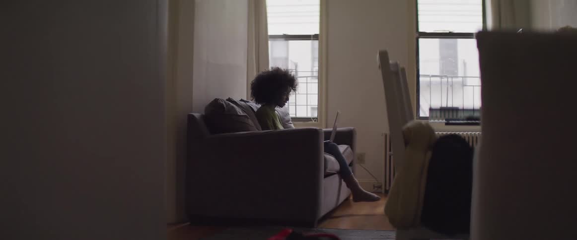 A woman sitting on a couch looking at a laptop
