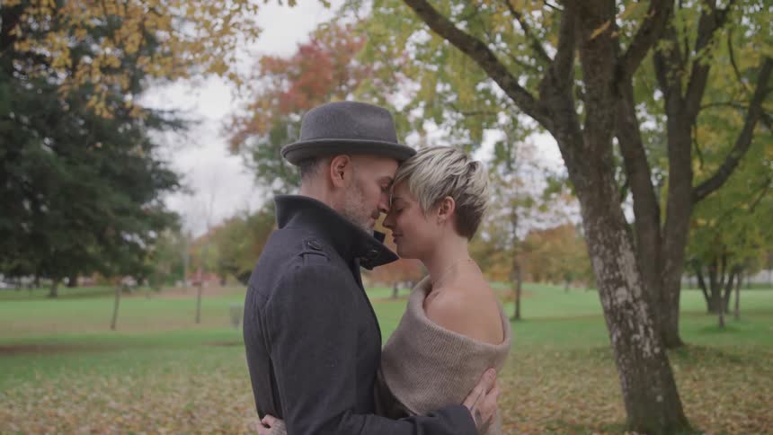 Romantic couple hugging touching foreheads at a park in the fall
