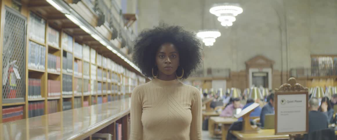 A woman stands next to a bookcase in a library