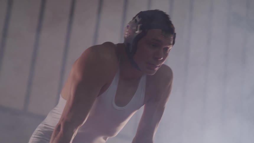 Wrestler leans over breathing heavily in foggy room as another runs past