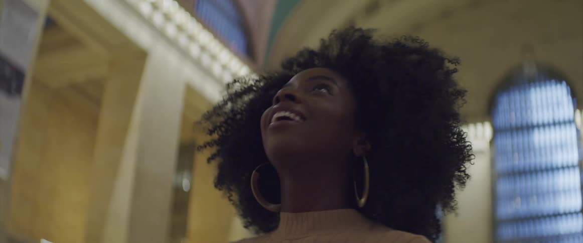 A woman smiles as she twirls looking up at a building ceiling in wonder