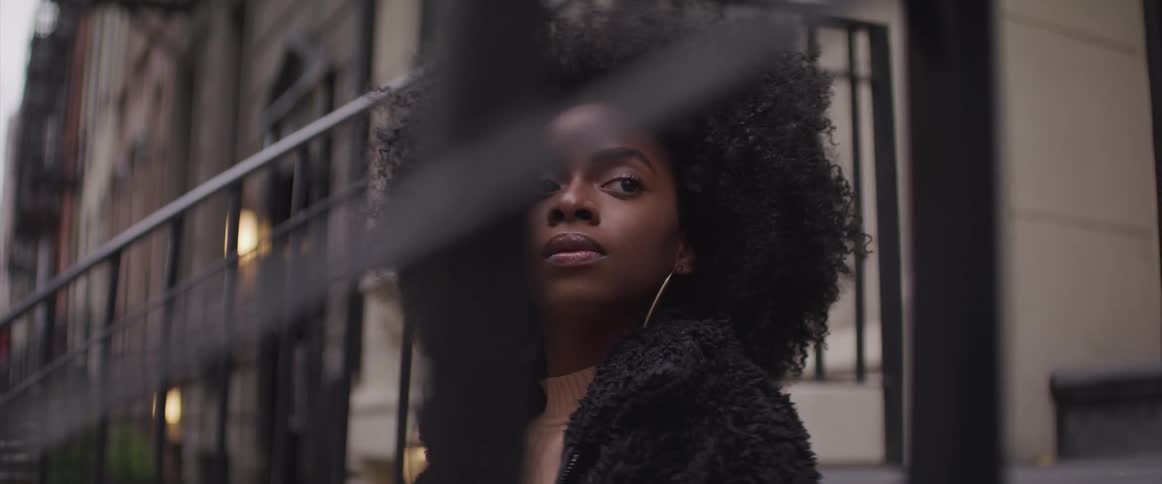 Young black woman sitting on steps of apartment building in a neighborhood