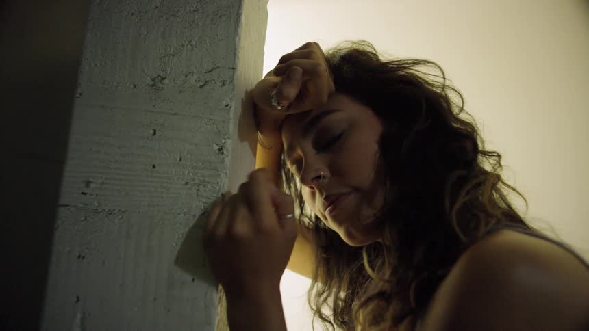 A woman leans up against a post seductively