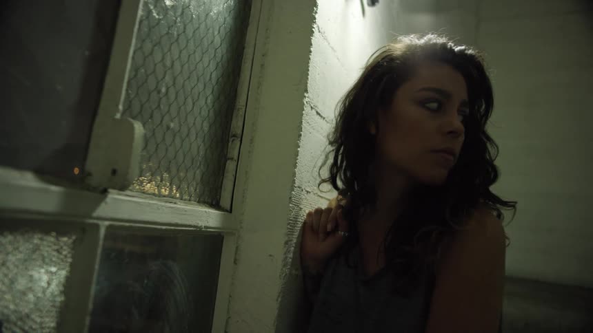 Woman stands near window inside a dimly lit room at night