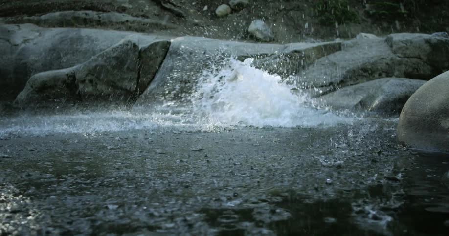 A man jumps off a rock and in to the water