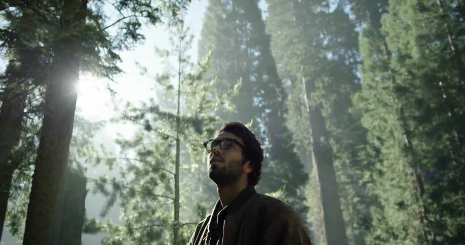 Man stands and looks around in the dense forest