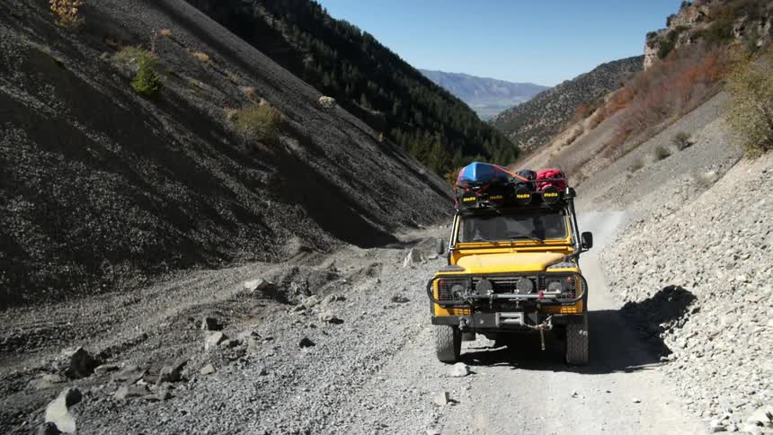 A yellow vehicle is driving uphill on a small path