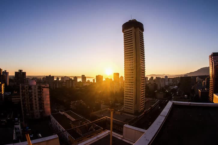 A city skyline with buildings and vehicles and the sunset in the background