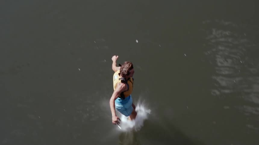 Man wearing life jacket jumps from cliff into water