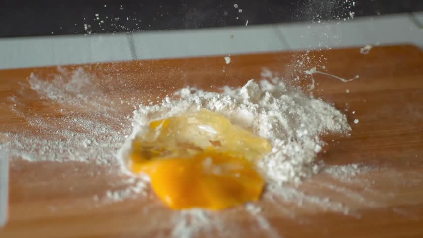 An egg dropping on to flour