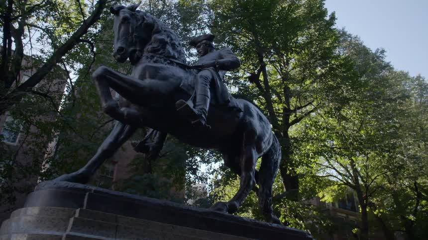 A statue of a soldier on a horse sits in front of apartment buildings