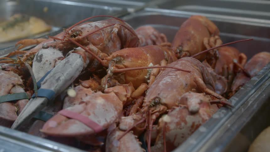 Pile of lobsters in a metal tray at a seafood market