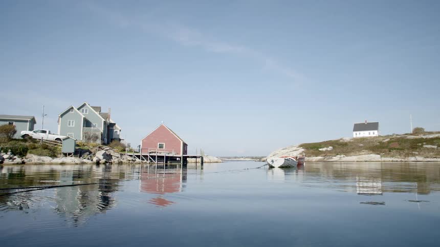 Shot of a lake with a boat on it from the level of the lake with houses on the land beside the lake on either side