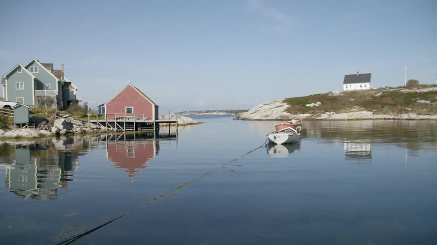 A boat sits in a lake next to a lake house and boat house