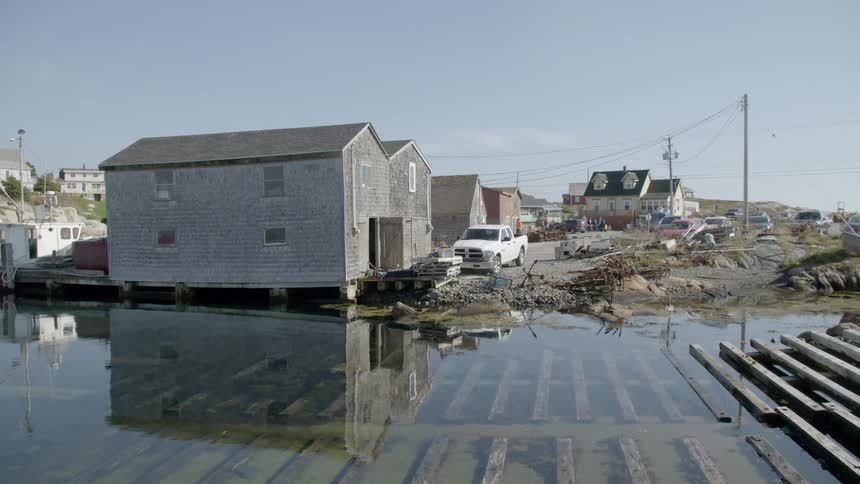 Homes sit in flooded water by a road and wood planks