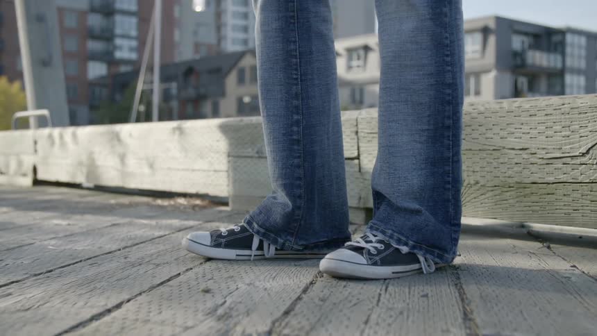 A male stands outside tapping his foot
