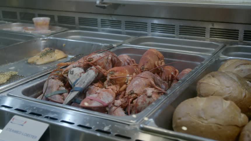 Trays of bread lobster and fish are lined up at a buffet