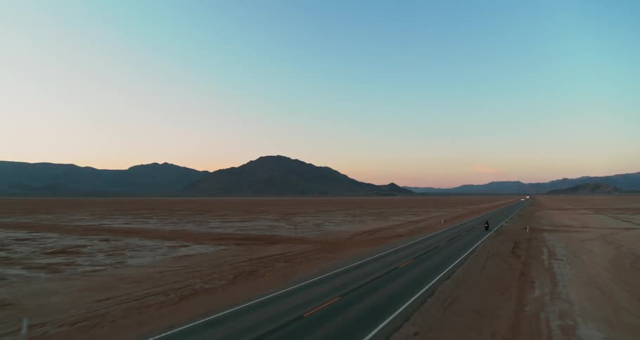 A motorcycle drives down a desert road