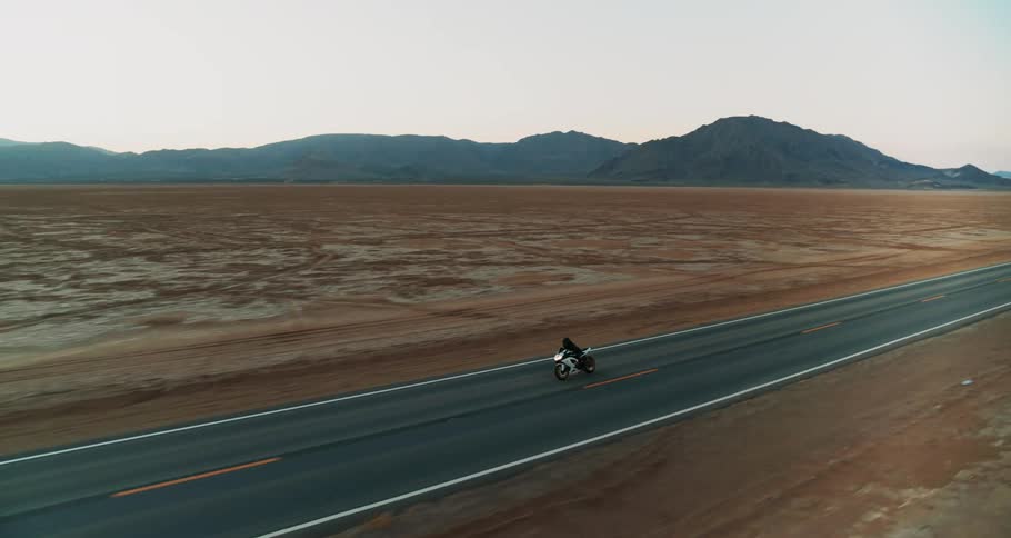 A person drives a motorcycle through a desert area