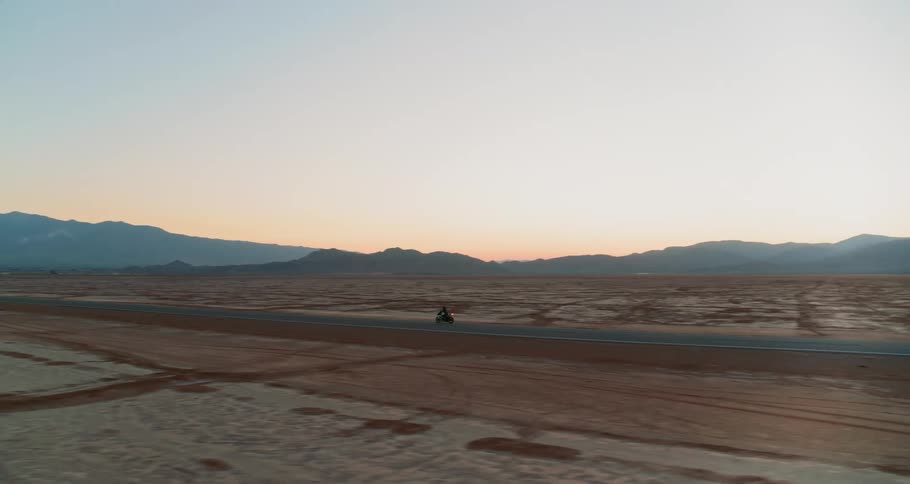 A motorcycle drives across the desert