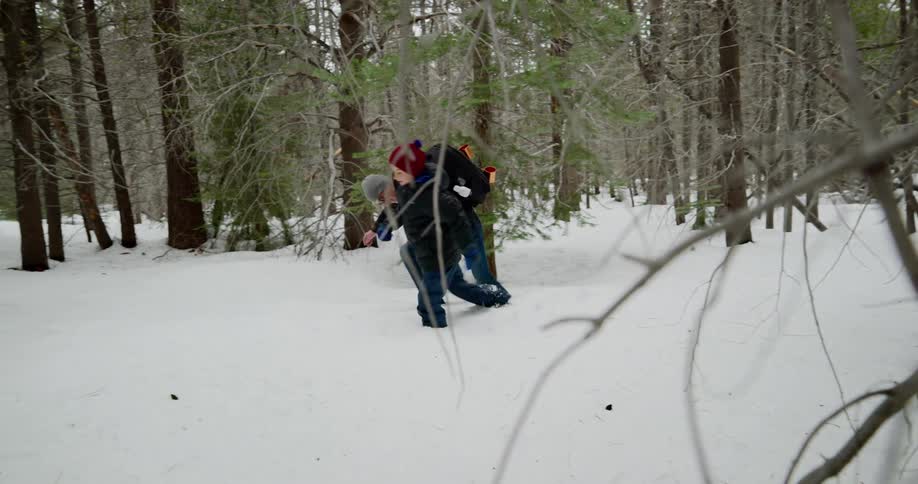 A father and son hike with difficulty though deep snow in a forest