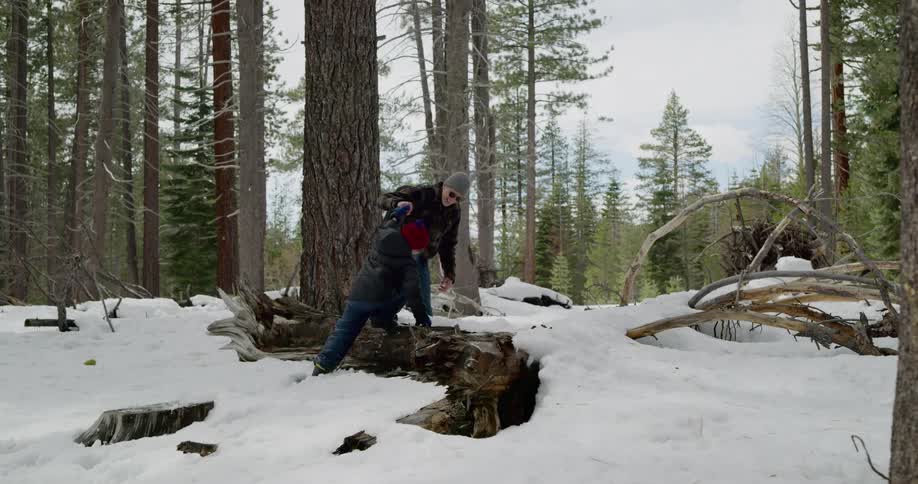 Father and son walk in the snow covered forest