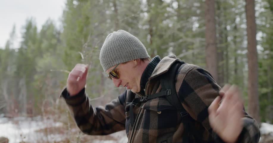 A hiker taking of his hat while standing in a forest