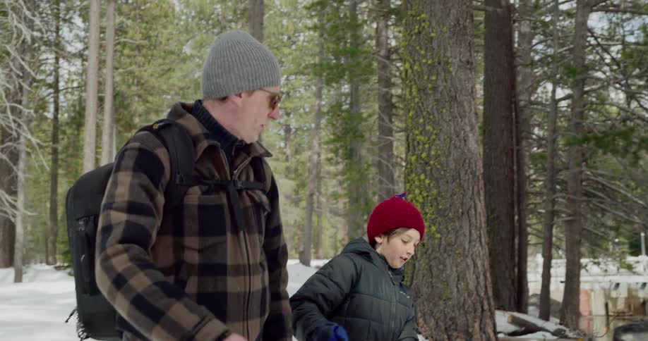 A man and a boy hiking through a snowy forest
