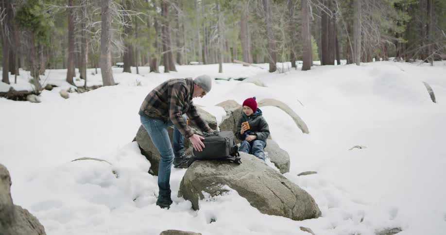 A man pulls cups from his backpack and hands one to his son