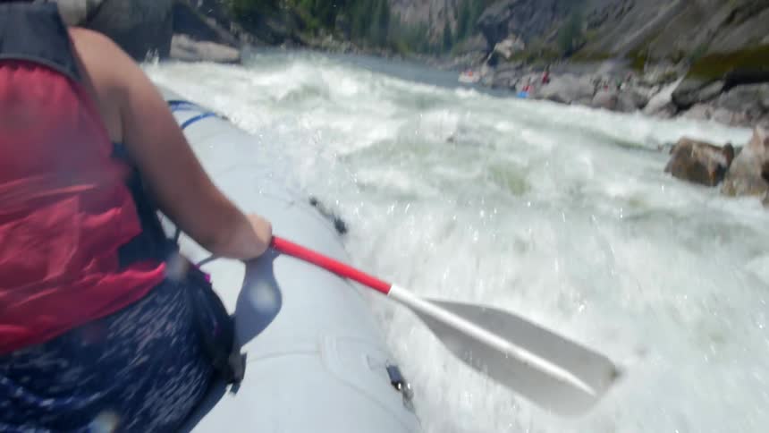 Woman laughing and crossing river rapids