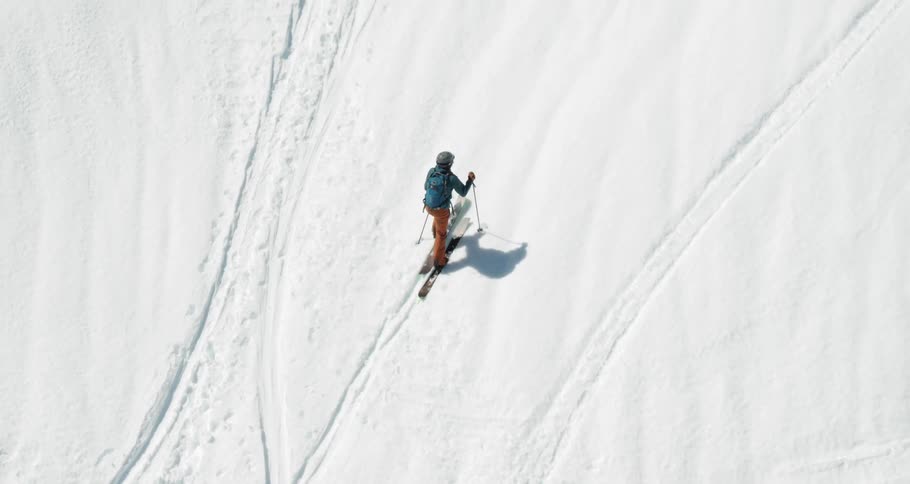 Aerial of cross country skier trekking up snow covered mountain
