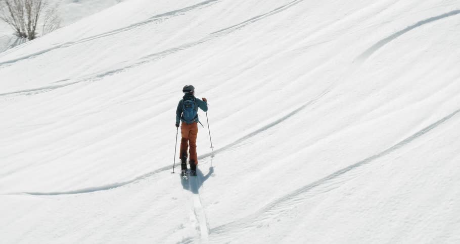 A person is climbing up the slope on skis