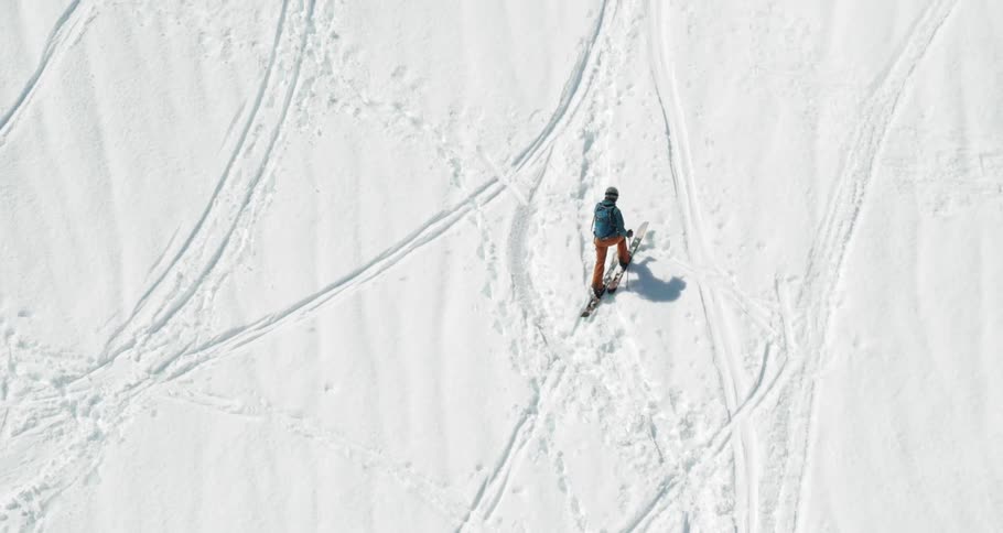 Cross country skier trekking up hill on a snow filled mountain