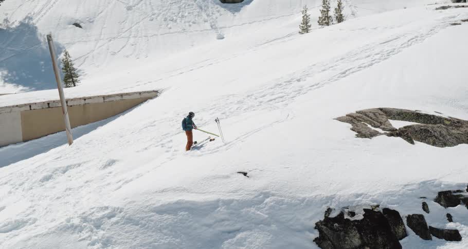 Person works with skies standing on snow covered slope