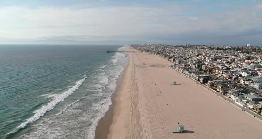 Waves rolling towards the beach with houses in the background